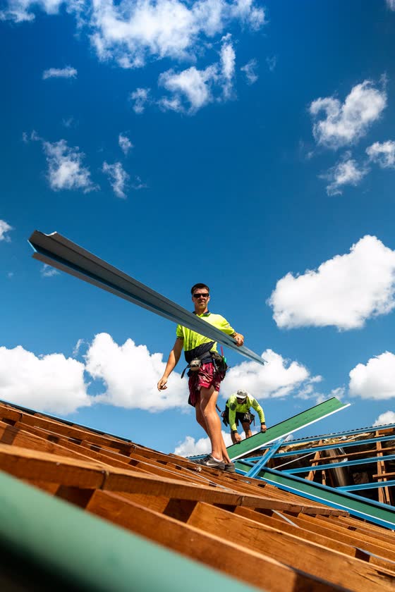 Roofer carrying a roof sheet against a blue sky
