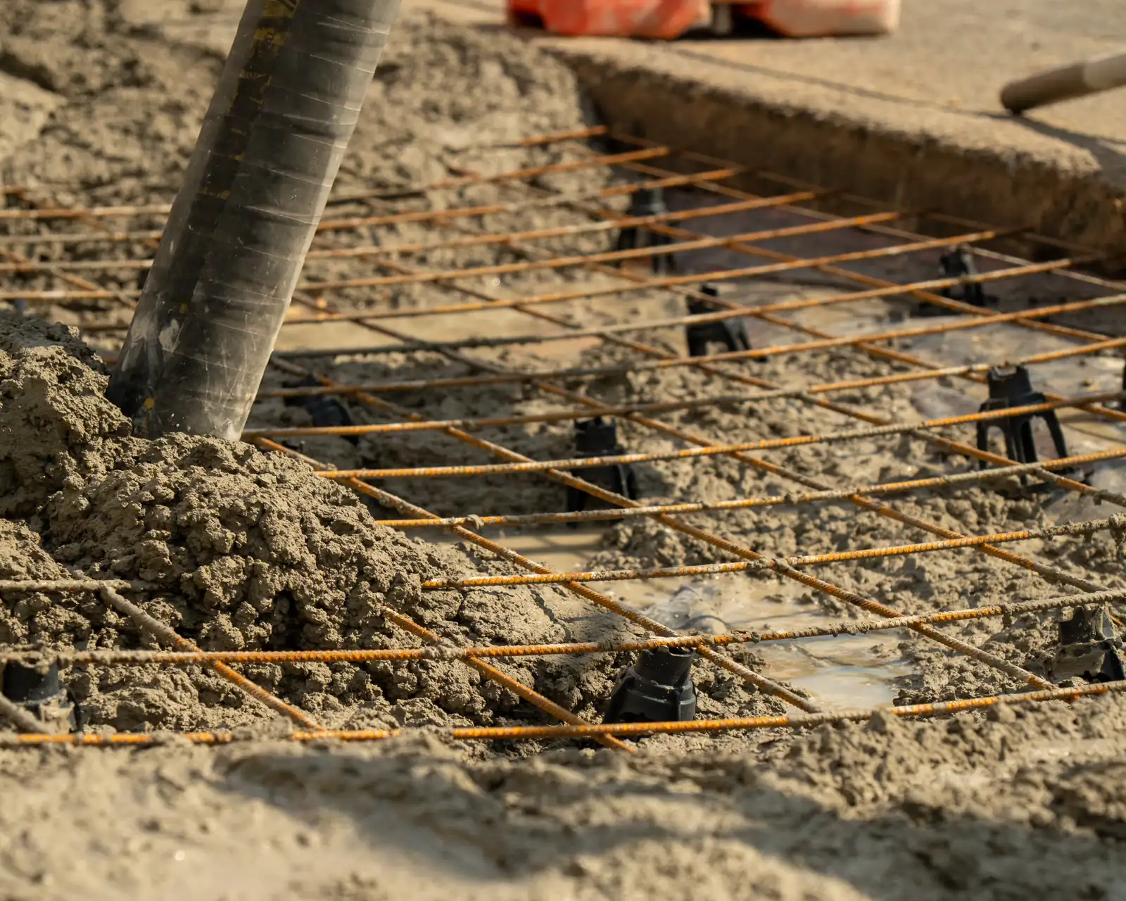 Concrete being poured over steel reinforcement mesh on a construction site